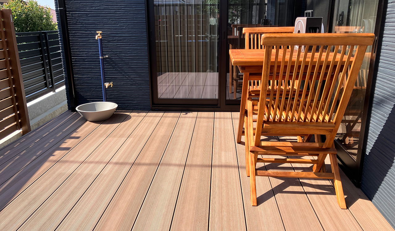 人工木製のウッドデッキはくつろぎの空間に最適です。ネイビー×ゴールドのおしゃれな立水栓がアクセント